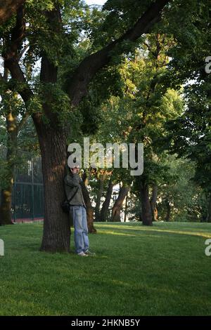 Ein Mann steht an einem Baum und telefoniert Stockfoto