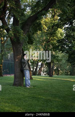 Ein Mann steht an einem Baum und telefoniert Stockfoto