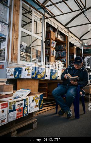 Ein Händler auf Kyjiws berühmtem Petrivka-Buchmarkt liest vor seinem Stand. Stockfoto