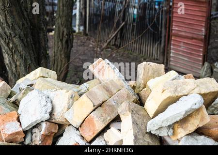 Ein Haufen alter gebrauchter Ziegelsteine mit Kratzern und Rissen von der alten Mauer in der Nähe des Grundstücks. Stockfoto