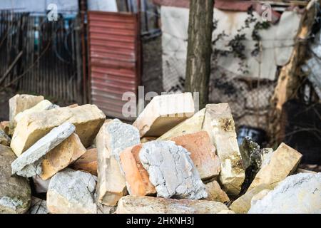 Ein Haufen alter gebrauchter Ziegelsteine mit Kratzern und Rissen von der alten Mauer in der Nähe des Grundstücks. Stockfoto