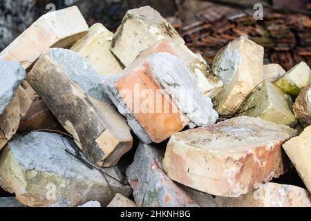 Ein Haufen alter gebrauchter Ziegelsteine mit Kratzern und Rissen von der alten Mauer in der Nähe des Grundstücks. Stockfoto