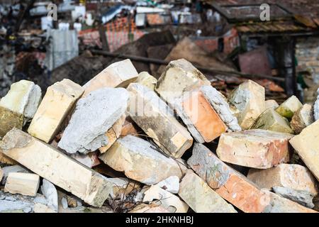 Ein Haufen alter gebrauchter Ziegelsteine mit Kratzern und Rissen von der alten Mauer in der Nähe des Grundstücks. Stockfoto