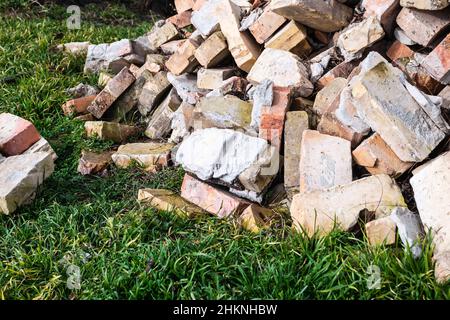 Ein Haufen alter gebrauchter Ziegelsteine mit Kratzern und Rissen von der alten Mauer in der Nähe des Grundstücks. Stockfoto