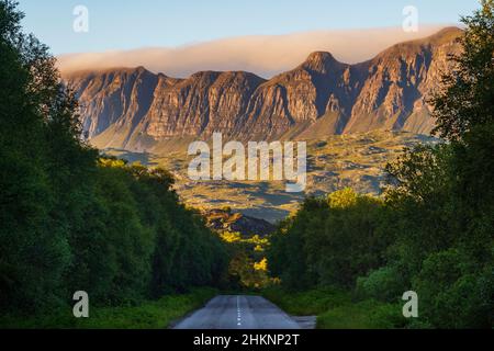 Die Bergkette des Knockan Crag National Nature Reserve bei Sonnenuntergang, von der zweispurigen Autobahn A385 in der Nähe von Elphin, Lairg, Schottland aus gesehen. Stockfoto