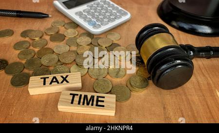Tax Time Text auf Holzblöcken mit Münzen, Gavel, Taschenrechner Hintergrund. Steuerkonzept. Stockfoto