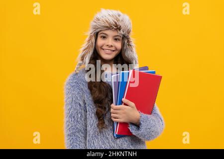 Glückliches Kind lange Haare in Hut mit Copybook auf gelbem Hintergrund, Bildung Stockfoto