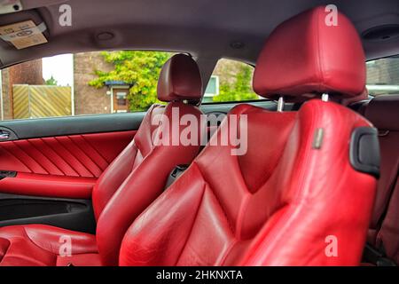 Teil aus rotem Leder mit Ziernähten. Innenraum des Luxuswagens. Stockfoto