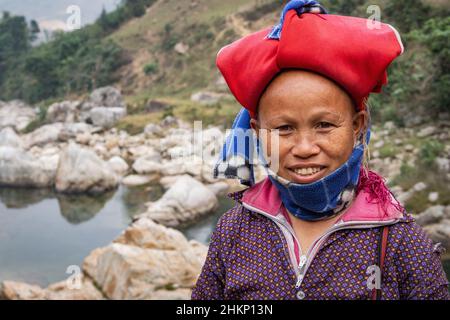 Fröhliche Frau aus der ethnischen Minderheit der Roten Dao, die eine typische Kopfbedeckung trägt und in der Nähe von Sapa, Lao Cai, Vietnam, lächelt. Stockfoto