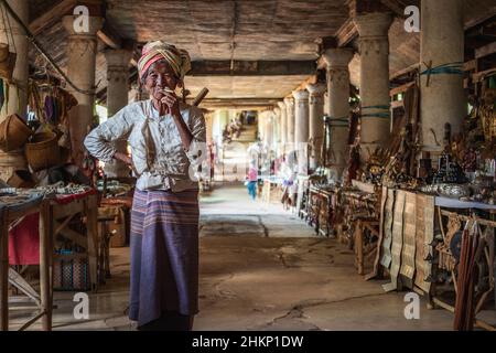 Eine alte burmesische Dame raucht eine Zigarre auf dem traditionellen Handwerksmarkt im Dorf Indein, Shan State, Myanmar (Burma). Stockfoto
