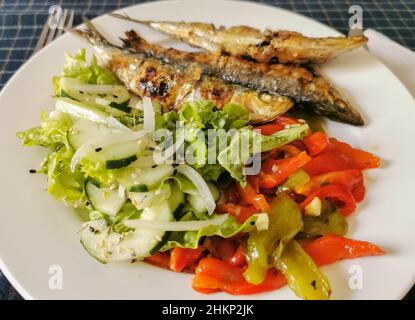 Blick auf plattierte Speisen, gesundes Fischgericht, typisches Gericht der portugiesischen regionalen Küche mit gegrillten Sardinen mit Salat: Rote Paprika, grüne Paprika, sesa Stockfoto