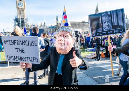 London, Großbritannien. 5th. Februar 2022. Eine Charikatur von Boris Johnson, Premierminister, fordert den Gesetzentwurf zur „Entrechtung der Benachteiligten“, der von einem Protestierenden hinter sich gestellt wird, sagt, er sei schuldig wie die Hölle und solle zurücktreten – macht Stimmen wichtig – Ein „Stop the Elections Bill“-Protest auf dem Parliament Square. Wenn das Gesetz angenommen würde, wäre es ein "Desaster für die Demokratie". Sie glauben nicht, dass der Wahlbetrug hoch genug ist, um die Verwendung einer Identifizierung bei der Abstimmung zu verdienen, was ihrer Meinung nach viele bereits marginalisierte Gruppen abschreckenlassen würde. Kredit: Guy Bell/Alamy Live Nachrichten Stockfoto