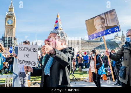 London, Großbritannien. 5th. Februar 2022. Eine Charikatur von Boris Johnson, Premierminister, fordert den Gesetzentwurf zur „Entrechtung der Benachteiligten“, der von einem Protestierenden hinter sich gestellt wird, sagt, er sei schuldig wie die Hölle und solle zurücktreten – macht Stimmen wichtig – Ein „Stop the Elections Bill“-Protest auf dem Parliament Square. Wenn das Gesetz angenommen würde, wäre es ein "Desaster für die Demokratie". Sie glauben nicht, dass der Wahlbetrug hoch genug ist, um die Verwendung einer Identifizierung bei der Abstimmung zu verdienen, was ihrer Meinung nach viele bereits marginalisierte Gruppen abschreckenlassen würde. Kredit: Guy Bell/Alamy Live Nachrichten Stockfoto
