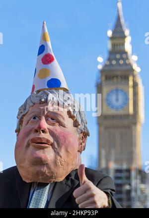 Mann, der in einer Boris Johnson Maske gekleidet ist und einen Partyhut vor dem Parlamentsgebäude trägt. Selektiver Fokus auf das Gesicht. London - 5th. Februar 2022 Stockfoto
