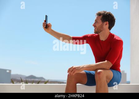 Selfie-Mann Fitness-Sportler, der ein Foto mit dem Mobiltelefon draußen auf dem Balkon oder im Fitnessstudio für soziale Medien gemacht hat. Aktiver Jugendstil Stockfoto