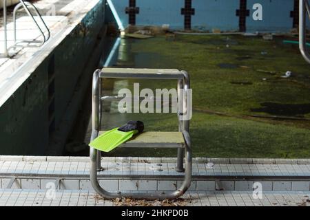 Geschlossener verlassene Swimmingpool, schmutziges Wasser voller Algen Stockfoto
