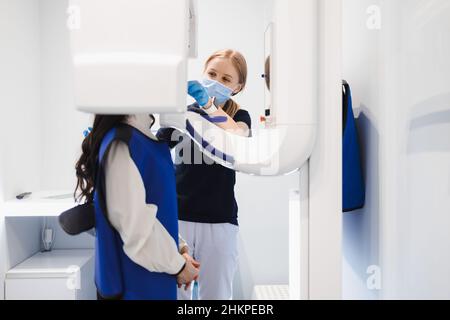 Weibliche Patientin machen einen zahnärztlichen Computertomographen. Der Radiologe führt einen CT-Scan des Kiefers durch. Frau, die in der Klinik eine Panoramaaufnahme der Zähne gemacht hat Stockfoto