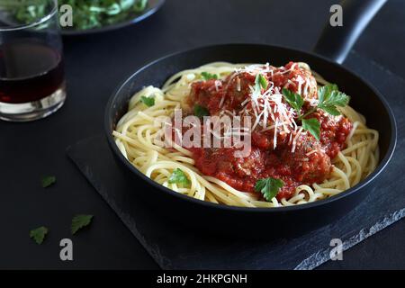 Spaghetti mit Fleischbällchen in Tomatensauce auf dunklem Hintergrund. Direkt darüber. Stockfoto