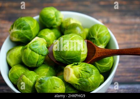 Rosenkohl (deutsch: Rosenkohl) auf einem Holztisch. Rosenkohl ist ein gesundes typisches Wintergemüse. Stockfoto