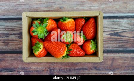 Draufsicht auf saftige Bio-Erdbeeren in einer umweltfreundlichen Kartonschachtel. Stockfoto