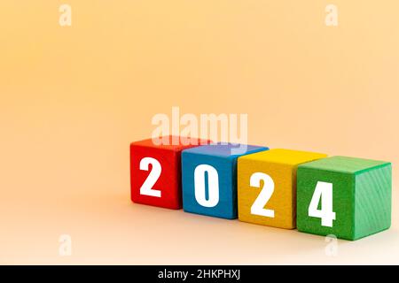 Jahr 2024 Weiße Zahlen auf bunt optimistischen Blöcken, Frohe Weihnachten und glückliches Neues Jahr, Aprikosenhintergrund Stockfoto