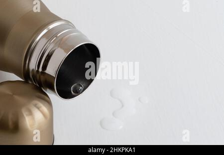 Transparenter Tropfen sauberen Wassers in Nahaufnahme im Hals von Metall-Thermoskannen auf weißem Hintergrund Stockfoto
