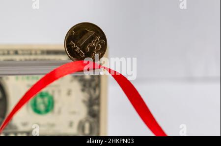 Eine Rubbelmünze in Nahaufnahme auf unscharfem Hintergrund des roten Bandes und einer Dollar-Banknote Stockfoto