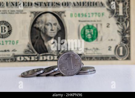 Chinas aktuelle 1-Yuan-Münze mit der Aufschrift - 1 Yuan, YI YUAN, Nahaufnahme der chinesischen Volksbank auf verschwommenem Hintergrund einer 1-Dollar-Banknote Stockfoto