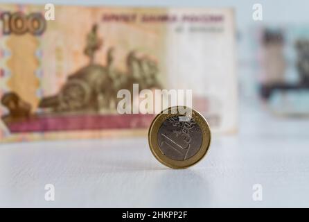 Nahaufnahme einer Euro-Münze vor verschwommenem Hintergrund von hundert russischen Rubel Stockfoto