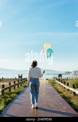 Anonyme Frau mit Luftballons, die über Eine Fußgängerbrücke gehen Stockfoto