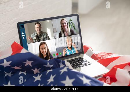 Reifer männlicher Soldat, der im Hauptquartier einen Laptop für die Kommunikation mit seiner Familie verwendet. Stockfoto