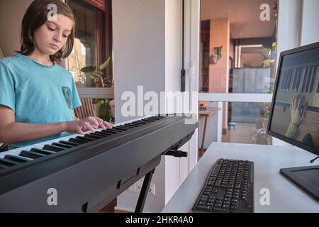 Teenager-Musiker spielt klassisches digitales Klavier zu Hause während des Online-Unterrichts zu Hause, soziale Distanz während der Quarantäne, Online-Bildungskonzept Stockfoto