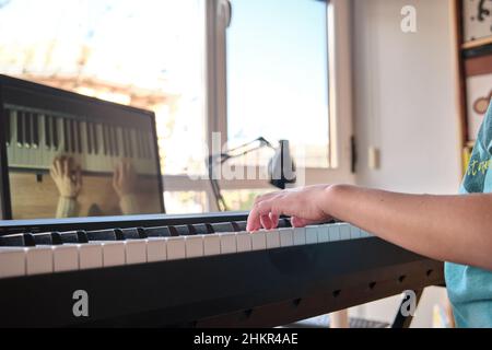 Teenager-Musiker spielt klassisches digitales Klavier zu Hause während des Online-Unterrichts zu Hause, soziale Distanz während der Quarantäne, Online-Bildungskonzept Stockfoto