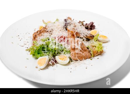 Warmer Salat mit gegrilltem Lachs und Wachteleiern. Isoliert auf weißem Hintergrund. Stockfoto