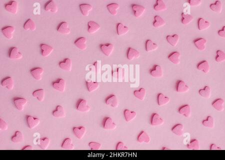 Muster. Rosa Süßwaren streut in Form von Herzen auf rosa Hintergrund, Textur Stockfoto