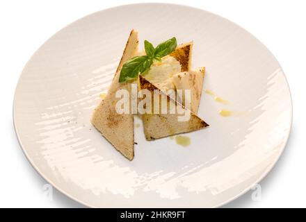 Venezianischer Kabeljau mit Toastscheiben und nativem Olivenöl extra und Basilikumblättern, auf weißem Grund auf einem Teller Stockfoto