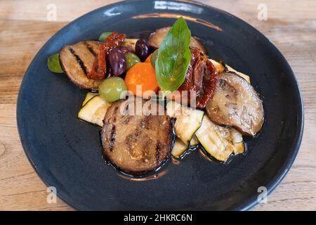 Gemischtes Gemüsegericht auf einem Teller mit gegrillter Aubergine, Zucchini mit Karotten und Oliven sowie getrockneten Tomaten. Stockfoto