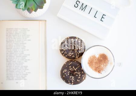 Blick auf einen Schreibtisch mit Kaffee und Donuts Stockfoto