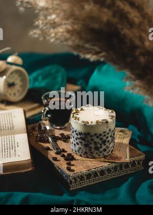 Ein Holztablett mit einer duftenden Kaffeekerze und Kaffee auf dem Bett. Hygge-Konzept. Entspannungsatmosphäre. Luxuriöser Lifestyle. Selektiver Fokus Stockfoto