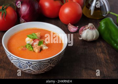 Gazpacho, typisch andalusische kalte Suppe auf Basis von Tomaten, Knoblauch, Pfeffer und Zwiebeln. Auf einem dunklen Holzhintergrund. Stockfoto