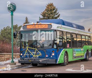 Fort Collins, CO, USA - 18. Januar 2022: Transferbus mit einer Fahrerin, ein Fahrrad auf Racks und Masken erforderte ein Banner an einem Halt. Transfort ist eine Stadt Stockfoto