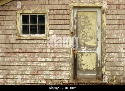 Die verwitterte Tür und das Fenster eines alten Holzgebäudes in der Nähe von Hampton, Prince Edward Island. Stockfoto