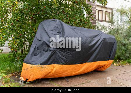 Motorrad auf dem Parkplatz mit einer Abdeckung bedeckt. Stockfoto