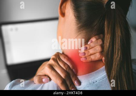 Nackenschmerzen nach der Arbeit am Computer. Junge Frau massiert Hals, um Schmerzen nach der Arbeit am pc zu lindern Stockfoto