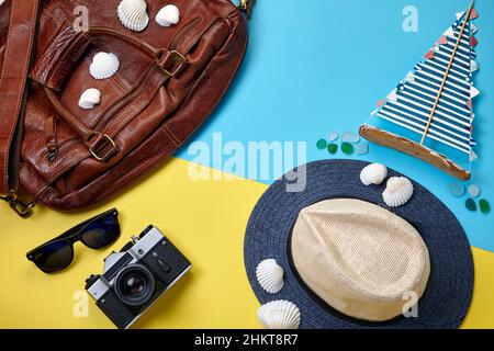 Road Ledertasche, Strohhut, Vintage Fotokamera, Muscheln und Segelyacht Stockfoto