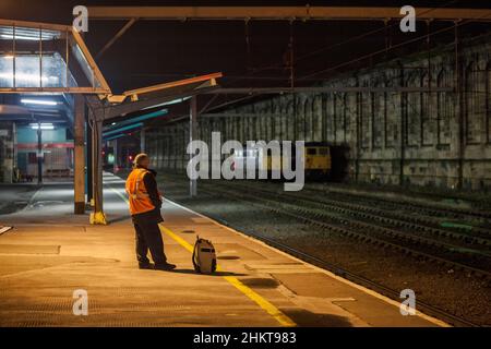 Freightliner-Zugfahrer wartet am Bahnhof Carlisle, um von einem Güterzug abgeholt zu werden, um ihn zurück nach Norden zu bringen Stockfoto