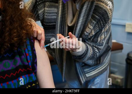 London, Großbritannien. 05th. Februar 2022. Ein Impfer verwaltet die Pfizer Covid-19 Booster Jab an eine Frau in einem Impfzentrum im Norden Londons. Kredit: SOPA Images Limited/Alamy Live Nachrichten Stockfoto