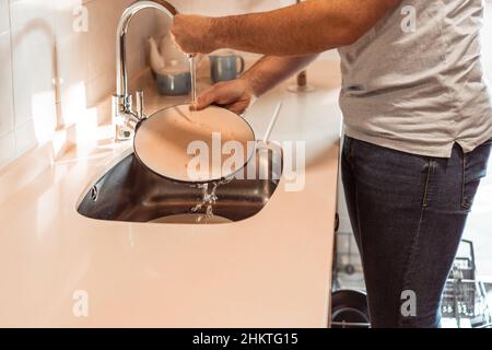 Ein Mann spülte schmutziges Geschirr im Waschbecken ab Stockfoto