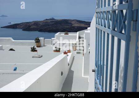 Santorini, Griechenland - 7. Mai 2021 : Eine Tür und eine Treppe führen zu einem Wohngebäude mit einem schönen Blick auf die Ägäis und den Vulkan Santor Stockfoto