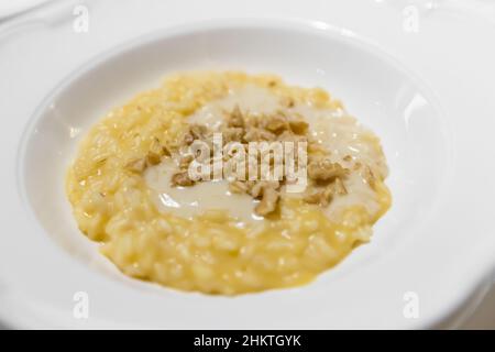 Safranrisotto mit Nüssen. Italienisches Gericht aus Safran, Reis- und Gemüsebrühe und Nüssen. Nahaufnahme. Stockfoto